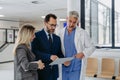 Pharmaceutical sales representative presenting new medication to doctors in medical building, presenting on tablet. Royalty Free Stock Photo