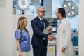 Pharmaceutical sales representative presenting new medication to doctors in medical building, shaking hands. Through Royalty Free Stock Photo