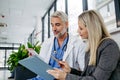 Pharmaceutical sales representative talking with doctor in medical building. Ambitious female medical rep presenting new