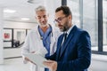 Pharmaceutical sales representative talking with doctor in medical building, presenting new medication on tablet Royalty Free Stock Photo