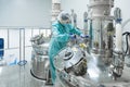 Pharmaceutical factory woman worker in protective clothing operating production line in sterile environment Royalty Free Stock Photo