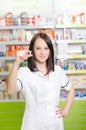 Pharmacist chemist woman show a pill. Pharmacy drugstore is background. Pretty, young laborant. Royalty Free Stock Photo