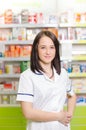 Pharmacist chemist woman show a pill. Pharmacy drugstore is background. Pretty, young laborant. Royalty Free Stock Photo