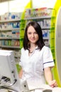 Pharmacist chemist woman show a pill. Pharmacy drugstore is background. Pretty, young laborant. Royalty Free Stock Photo