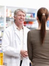 Pharmacist conversing with customer. Portrait of mature pharmacist conversing with customer at drugstore. Royalty Free Stock Photo