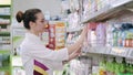 A young woman in white uniform sorting the merch in a drug store