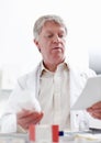Pharmacist examining medicine and prescription. Portrait of careful mature pharmacist looking examining while looking at