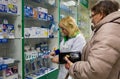 The pharmacist helps an elderly woman with a choice of goods