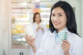 Pharmacist holds a packet of pills in her hands. Then she shows a thumbs up. A woman is standing in the middle of a pharmacy