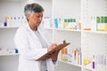 Pharmacist, medicine and a woman writing on a clipboard in a pharmacy for inventory or checklist. Mature female employee Royalty Free Stock Photo