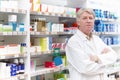 Pharmacist near medical store. Portrait of mature pharmacist standing near shelf at medical store. Royalty Free Stock Photo