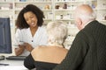 Pharmacist in pharmacy with senior couple
