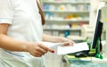 Pharmacist with prescriptions in front of medicines at drugstore
