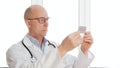 Pharmacist in white coat reading annotation on tablet blister on window background in drugstore. Portrait pharmacist