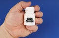 On a blue background in the hands of a man is a white jar with the inscription - Black Cohosh Royalty Free Stock Photo