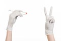 Pharmacology and Medical theme: doctor's hand in a white glove holding tweezers with red pill capsule isolated on white background Royalty Free Stock Photo