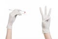 Pharmacology and Medical theme: doctor's hand in a white glove holding tweezers with red pill capsule isolated on white background Royalty Free Stock Photo