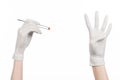 Pharmacology and Medical theme: doctor's hand in a white glove holding tweezers with red pill capsule isolated on white background Royalty Free Stock Photo