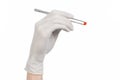 Pharmacology and Medical theme: doctor's hand in a white glove holding tweezers with red pill capsule isolated on white background Royalty Free Stock Photo