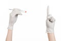 Pharmacology and Medical theme: doctor's hand in a white glove holding tweezers with red pill capsule isolated on white background Royalty Free Stock Photo