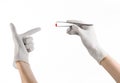 Pharmacology and Medical theme: doctor's hand in a white glove holding tweezers with red pill capsule isolated on white background Royalty Free Stock Photo