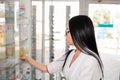 Pharmacy and Apothecary-seller. A woman pharmacist in glasses takes out medicines from a shop window. In profile