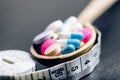 Pharmacy background on a black table with measuring tape. Tablets on a wooden spoon. Pills. Medicine and healthy. Close up of caps