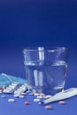 Pharmacy background on a blue background. Tablets on a blue background. Pills, Thermometer and water. Medicine and Royalty Free Stock Photo