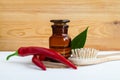 Pharmacy bottle with red chili pepper extract tincture, infusion, oil, fresh chili pepper pods and wooden hair brush. Royalty Free Stock Photo