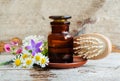 Pharmacy bottle, wild flowers and wooden hair brush. Herbal tincture essential oil, infusion, extract. Old wooden background. Royalty Free Stock Photo