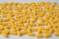 Pharmacy concept of handful of yellow pills tablets lying on white surface