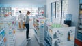 Pharmacy Drugstore: Beautiful Young Woman Chooses to Buy Medicine, Drugs, Vitamins, Searches for the