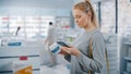 Pharmacy Drugstore: Portrait of a Beautiful Caucasian Woman Using Smartphone Search to Best Cream