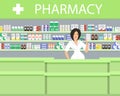 Pharmacy in a green color. The pharmacist woman stands near the shelves with medicines