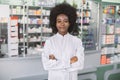 Pharmacy, healthcare concept. Young pretty smiling African dark skinned woman pharmacist in white coat, standing in