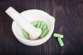 Pharmacy pestle and mortar with green capsules Royalty Free Stock Photo