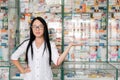 Pharmacy and pharmacist-seller. Female pharmacist with glasses posing on the background of shop Windows and pointing. Copy space