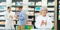 In pharmacy, senior female specialist holds and shows new remedy for moisturizing delicate skin