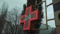 Pharmacy sign, red cross pharmacy sign or symbol on the building facade view from the street against a cloudy sky Royalty Free Stock Photo