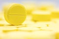 Pharmacy theme, Heap of yellow round medicine tablet antibiotic pills. Shallow DOF