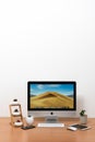 IMac computer, keyboard, magic mouse, iPhone X, iPad mini, plant vase and cactus pots on wooden table Royalty Free Stock Photo