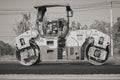 Zoom Side View Black and White Worker and Road Roller on Asphalt Road