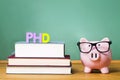 PhD degree theme with textbooks and piggy bank with glasses Royalty Free Stock Photo