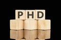 PHD text assembled from wooden cubes on a black background