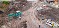 Top or Aerial view of construction site with many labor or worker working, buildings and green backhoe or Crawler Loader digging