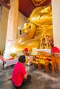 Red shirt woman worshiping reclining golden Buddha image