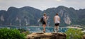 Two foreign tourists stand on the top of the hill overlooking island of phi phi and the sea passenger ship with mountain