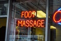 Red neon sign in a large store window that says Foot Massage