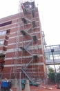 Long scaffolding with steps on the side of a tall brick building in a city Royalty Free Stock Photo