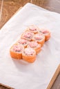 Philadelphia roll sushi with salmon and cream cheese and mayo on top on white crumpled paper background